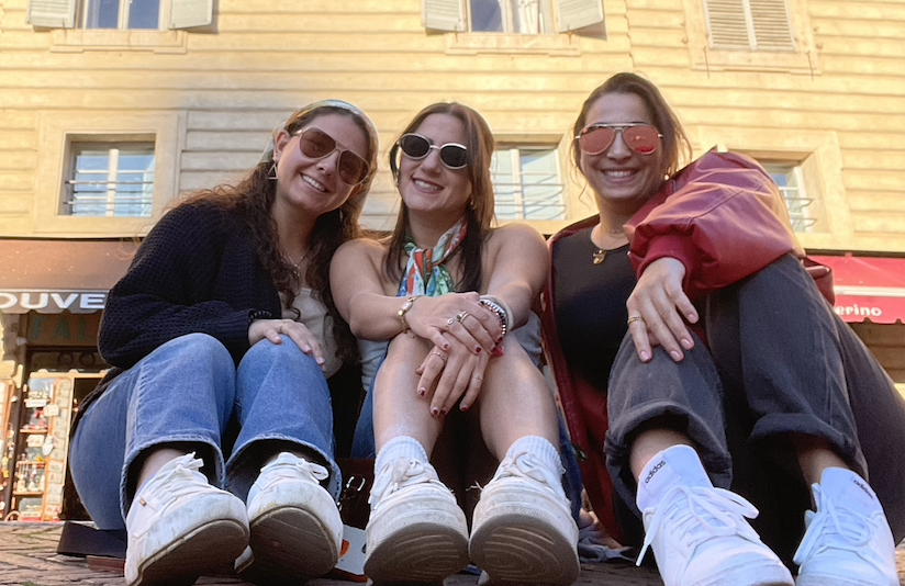 Three girls smiling sitting on the ground in Italy